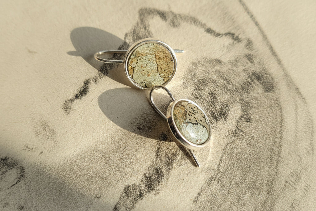 Pair of earrings with stone-like centers on a textured surface