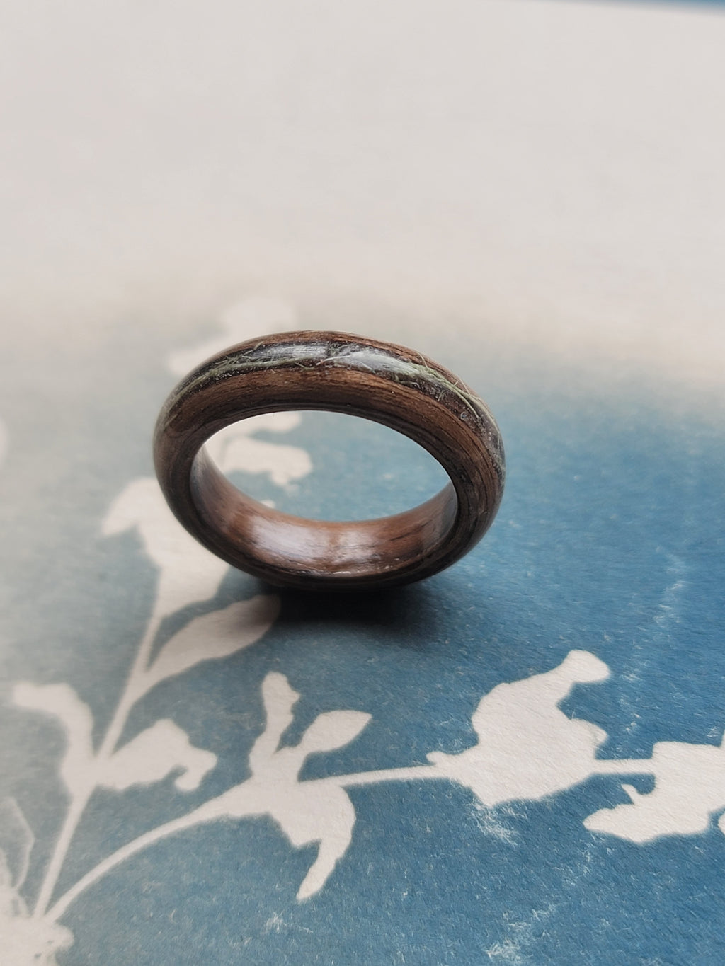 Wooden ring on a textured blue surface with floral patterns