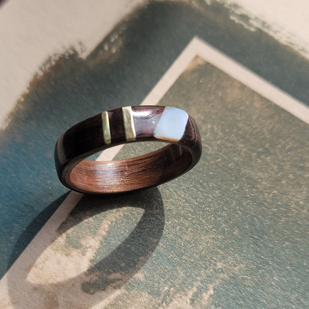 Wooden ring with a metallic band on a textured surface