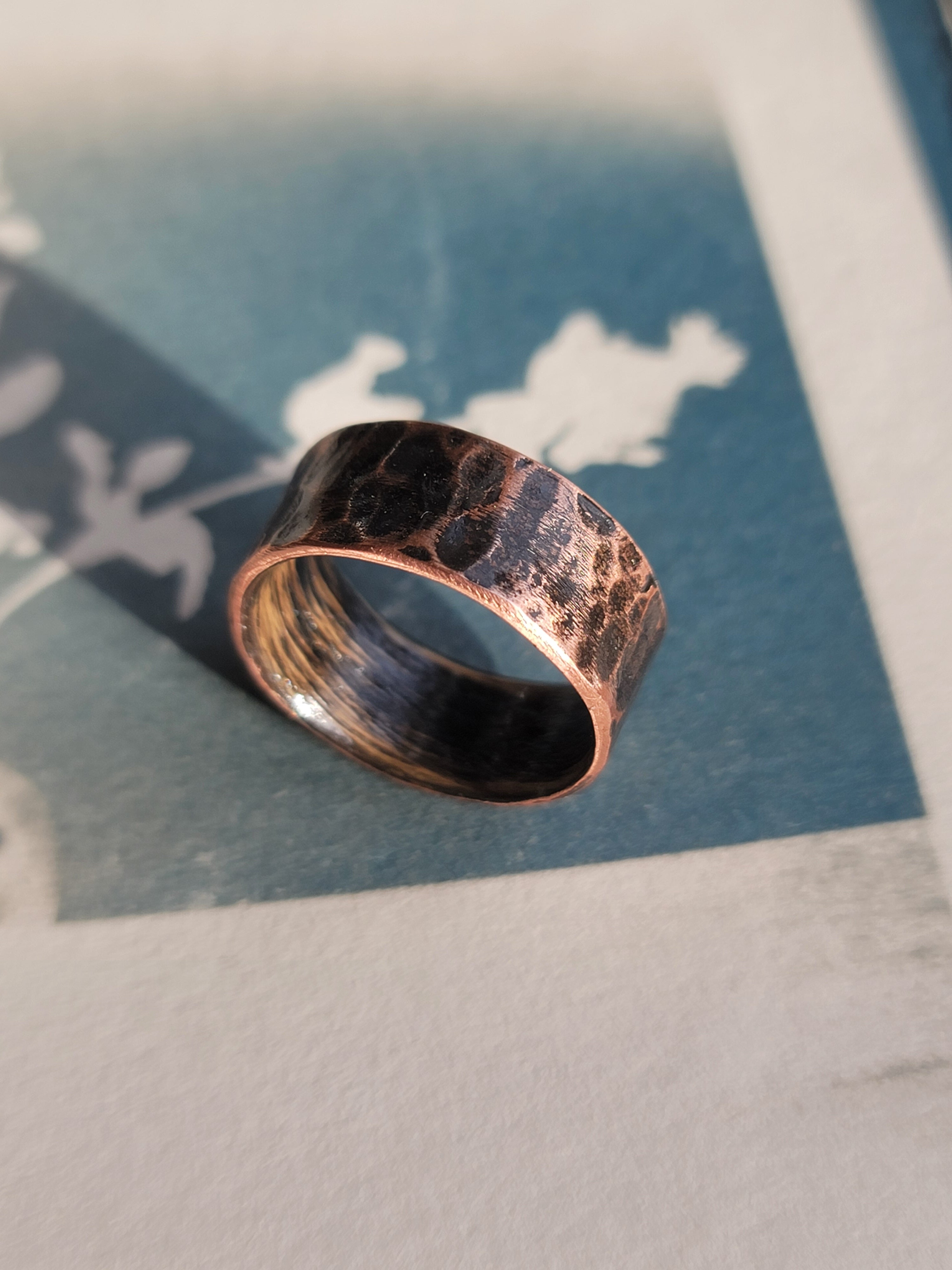 Hammered copper ring on a textured surface