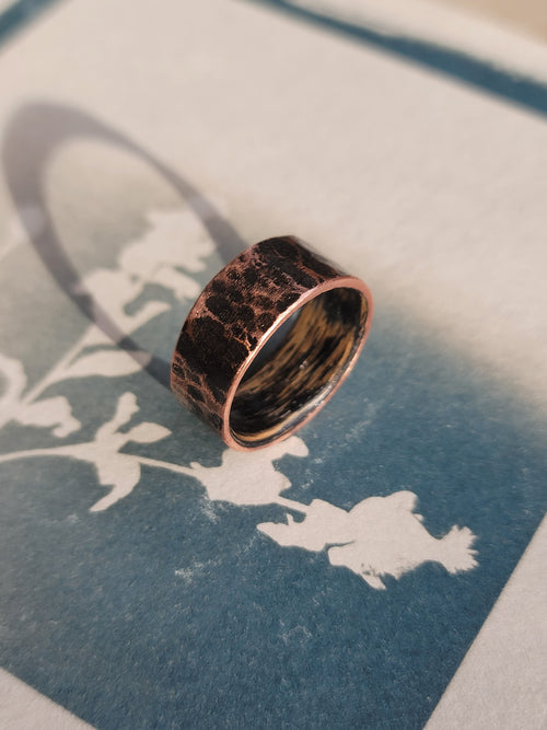 Copper ring on a textured surface with a blue and white abstract design