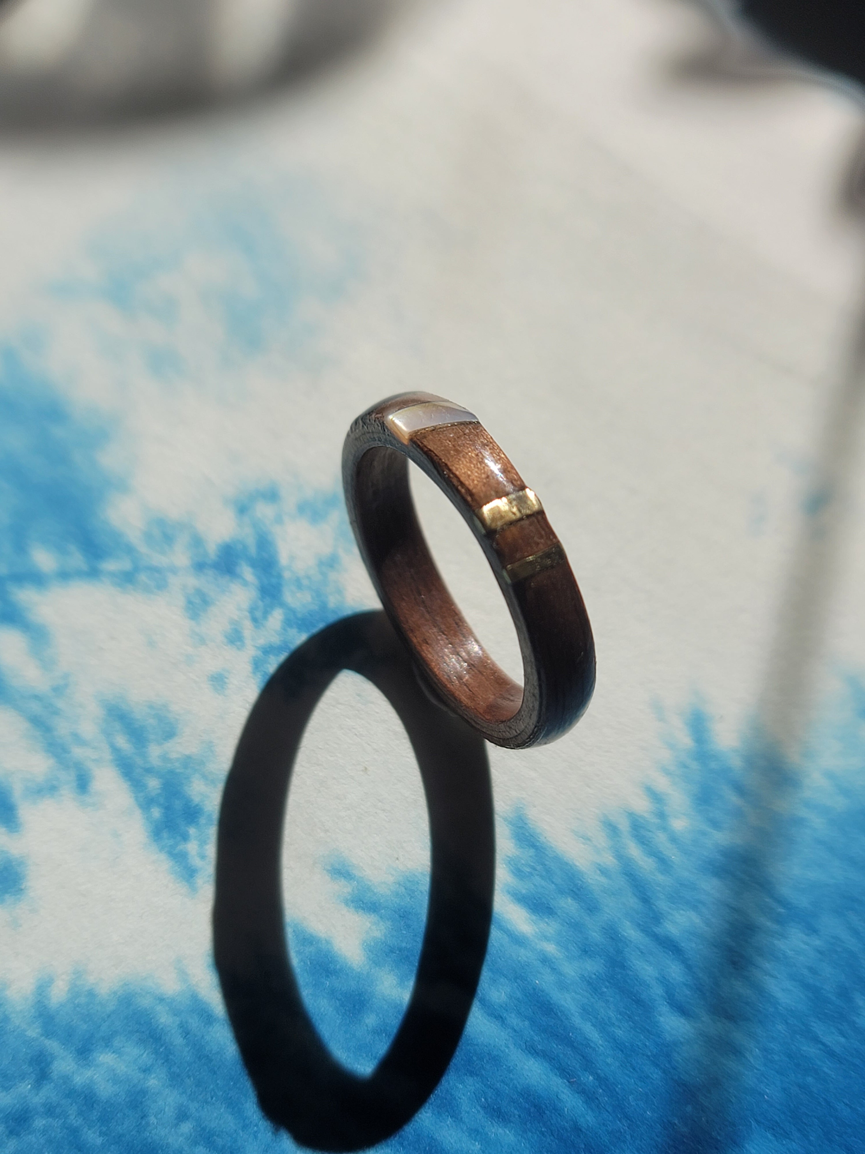 Wooden ring with gold accent on a textured blue and white surface