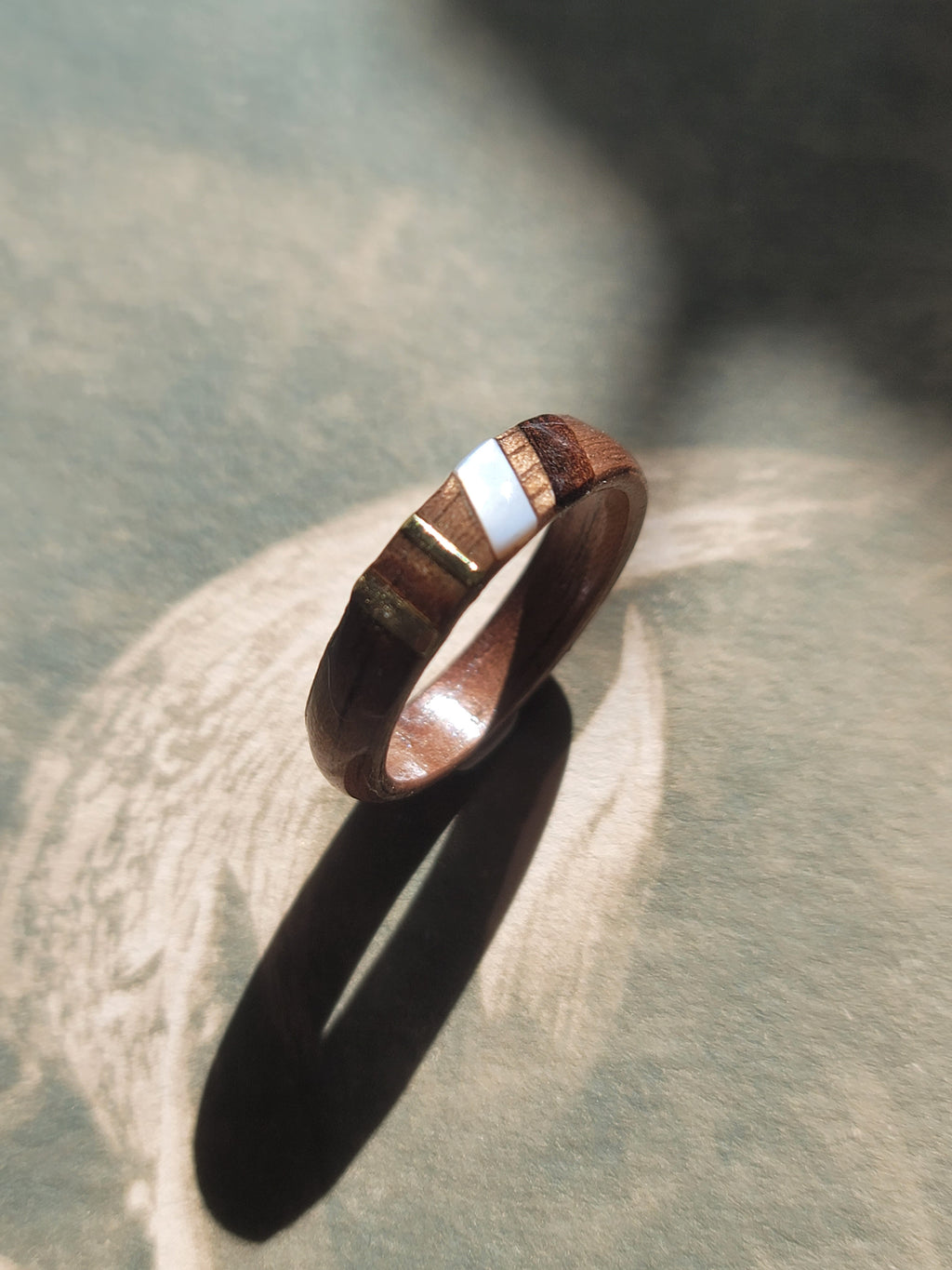 Wooden ring with silver inlay on a textured surface