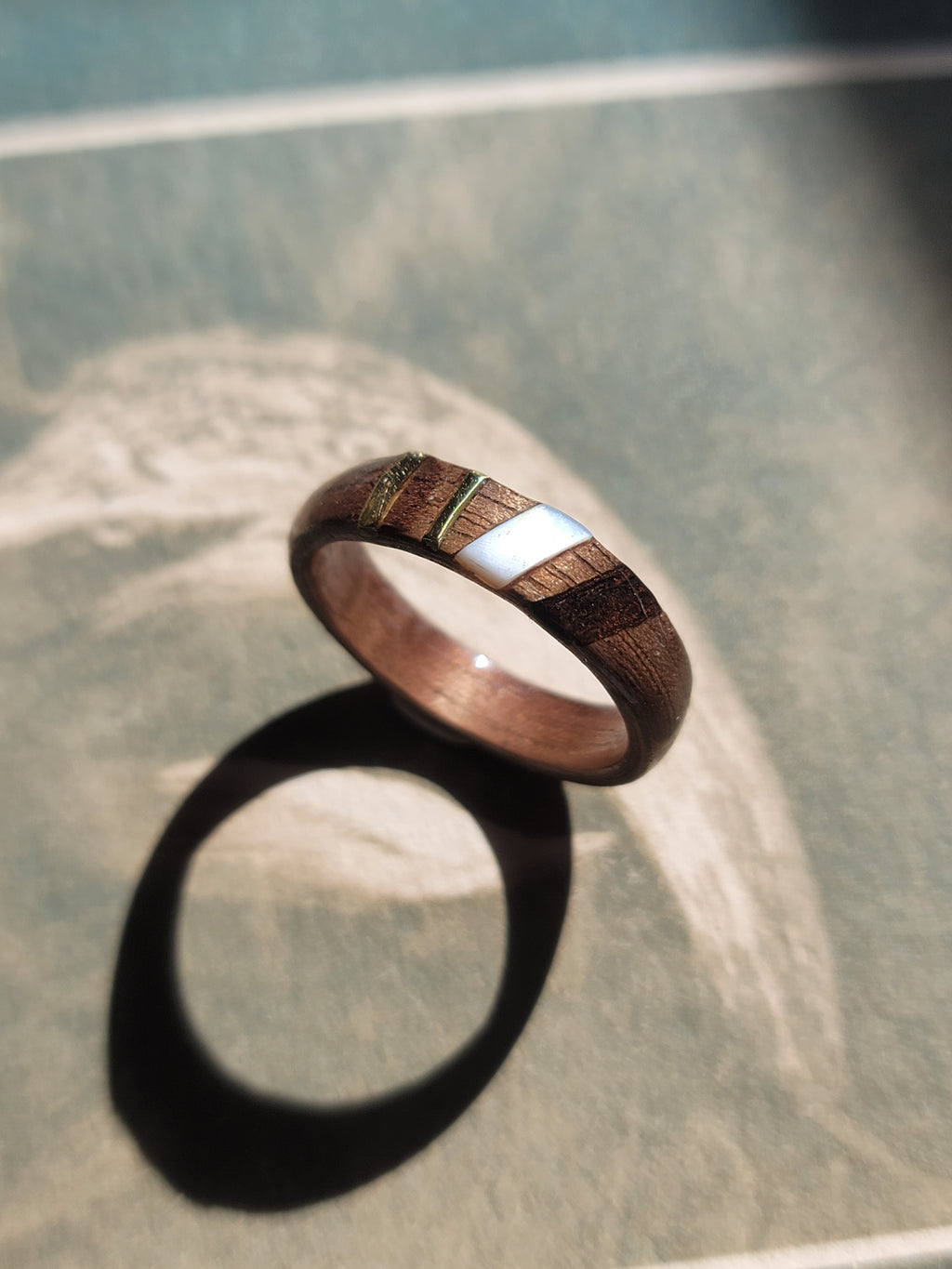 Wooden ring with silver inlay on a textured surface