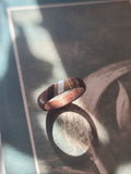 Wooden ring with a striped pattern on a textured surface