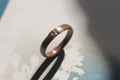 Wooden ring with copper and mother of pearl inlays on a textured background