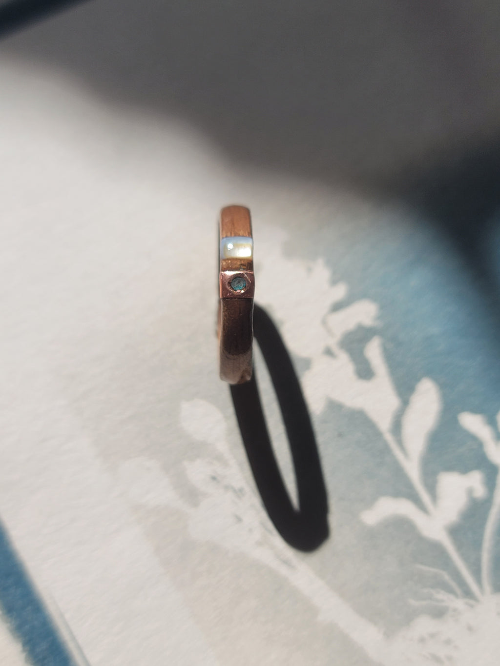 Wooden ring with copper and green verdigris on a white fabric background