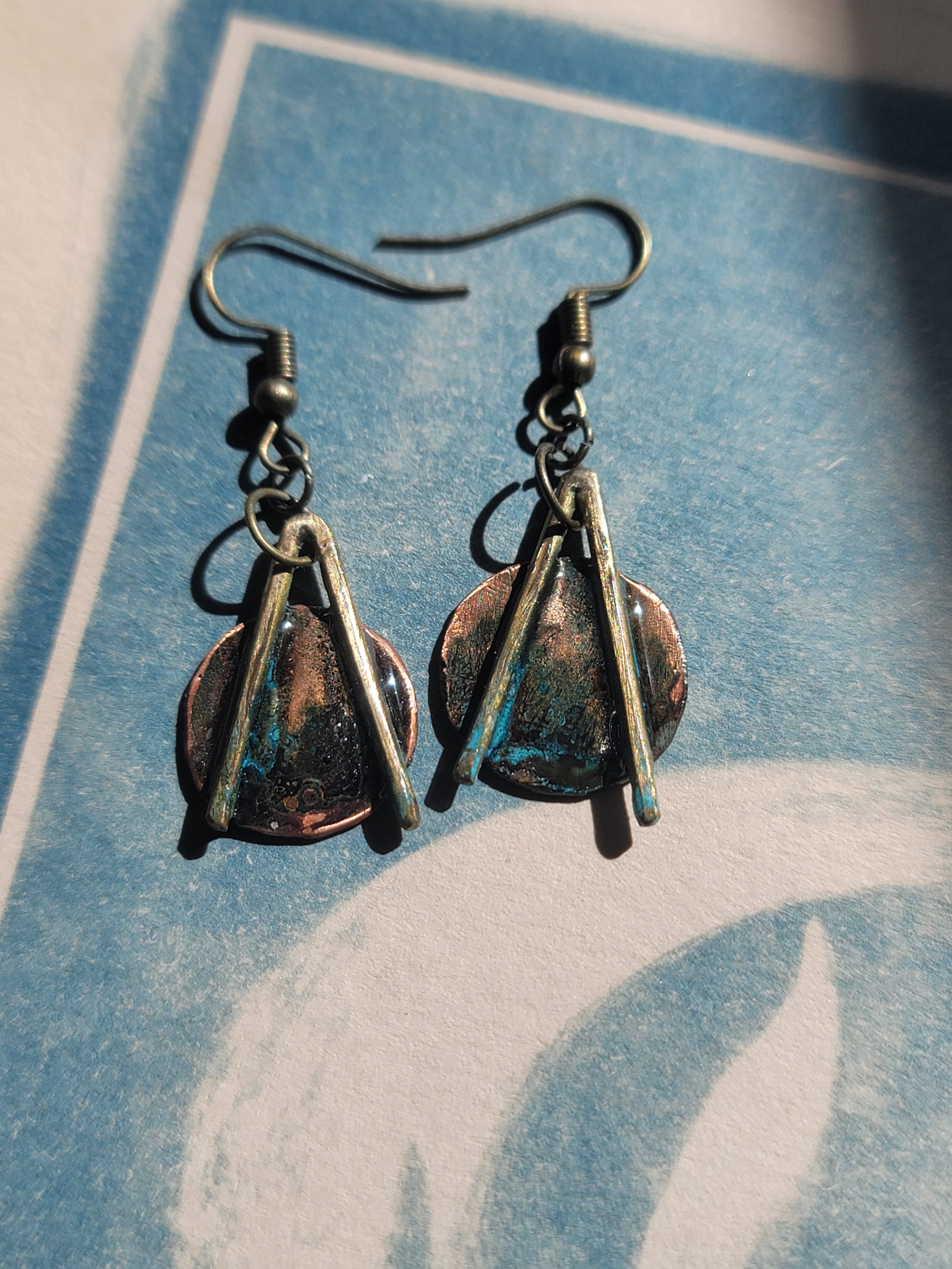 Pair of earrings made from copper discs on a blue and white background