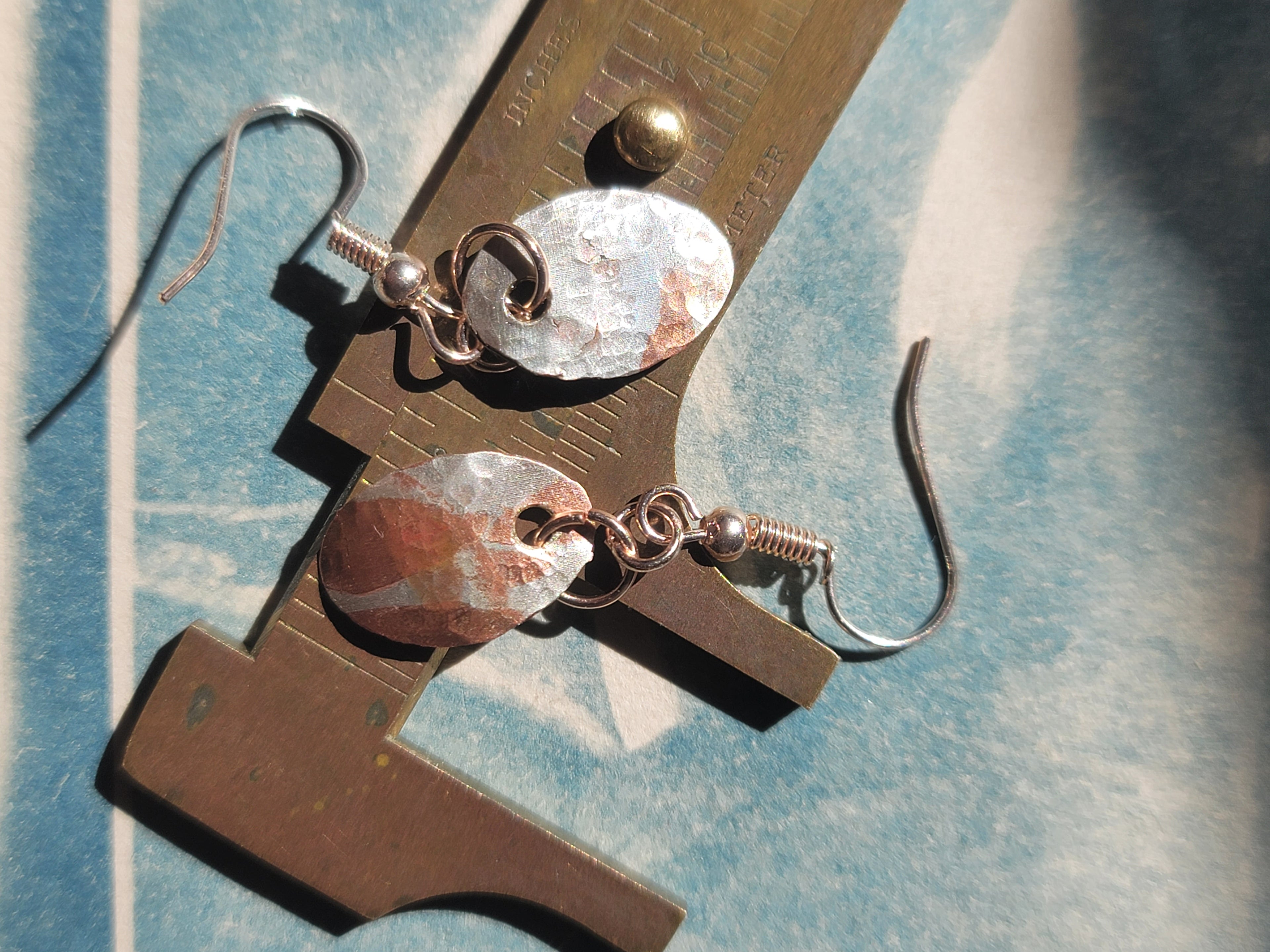 Pair of earrings on a metal stand with a blue and white background