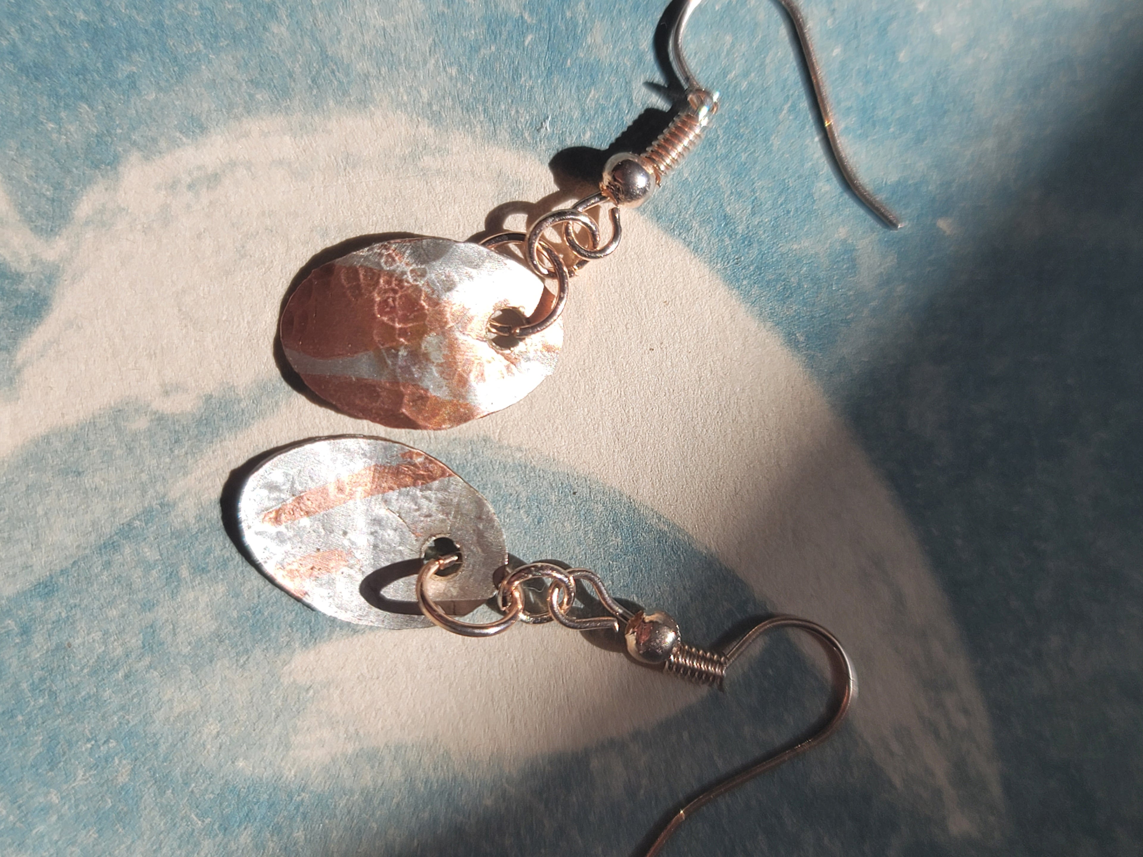 Pair of copper-colored earrings on a textured blue surface