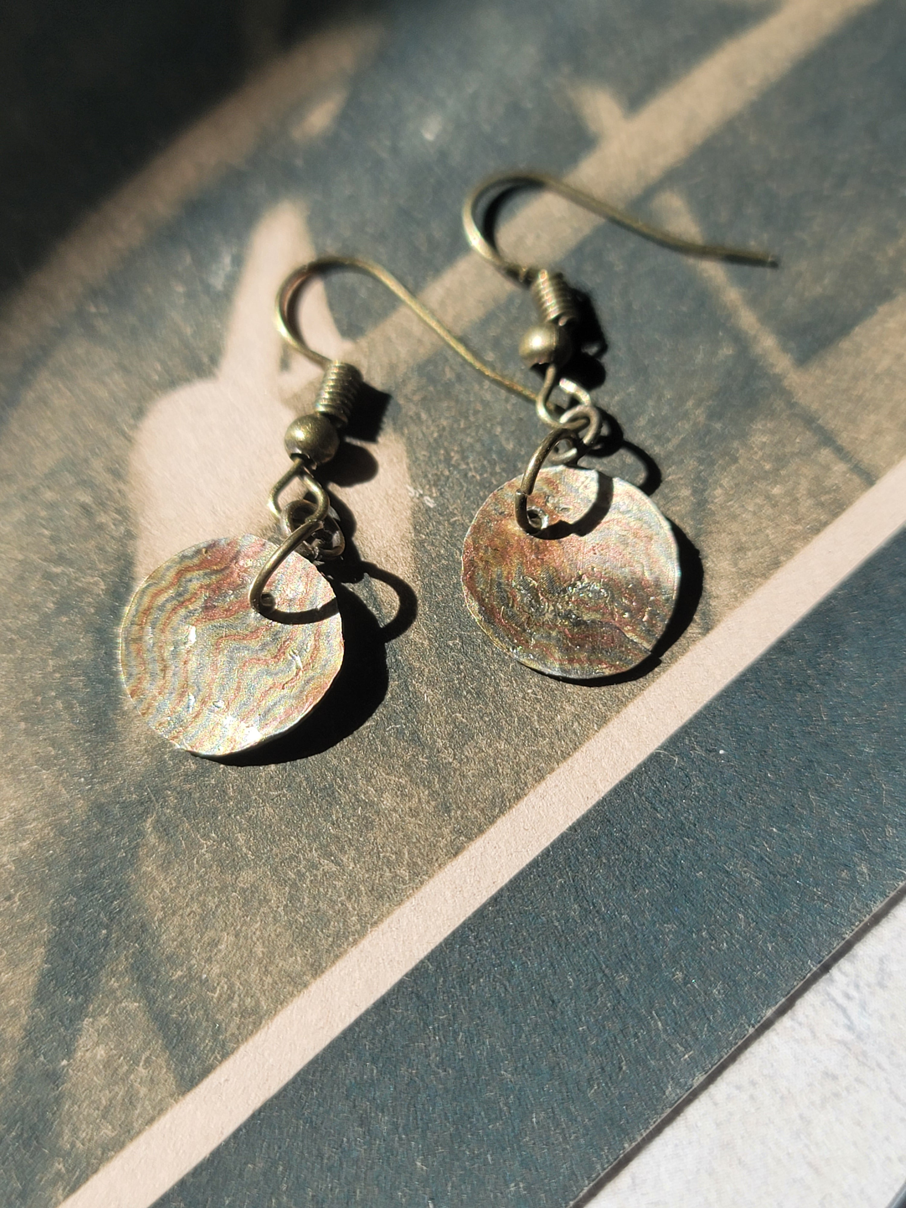 Pair of earrings with circular designs on a textured surface