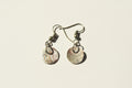 Pair of earrings with shell-like designs on a textured surface