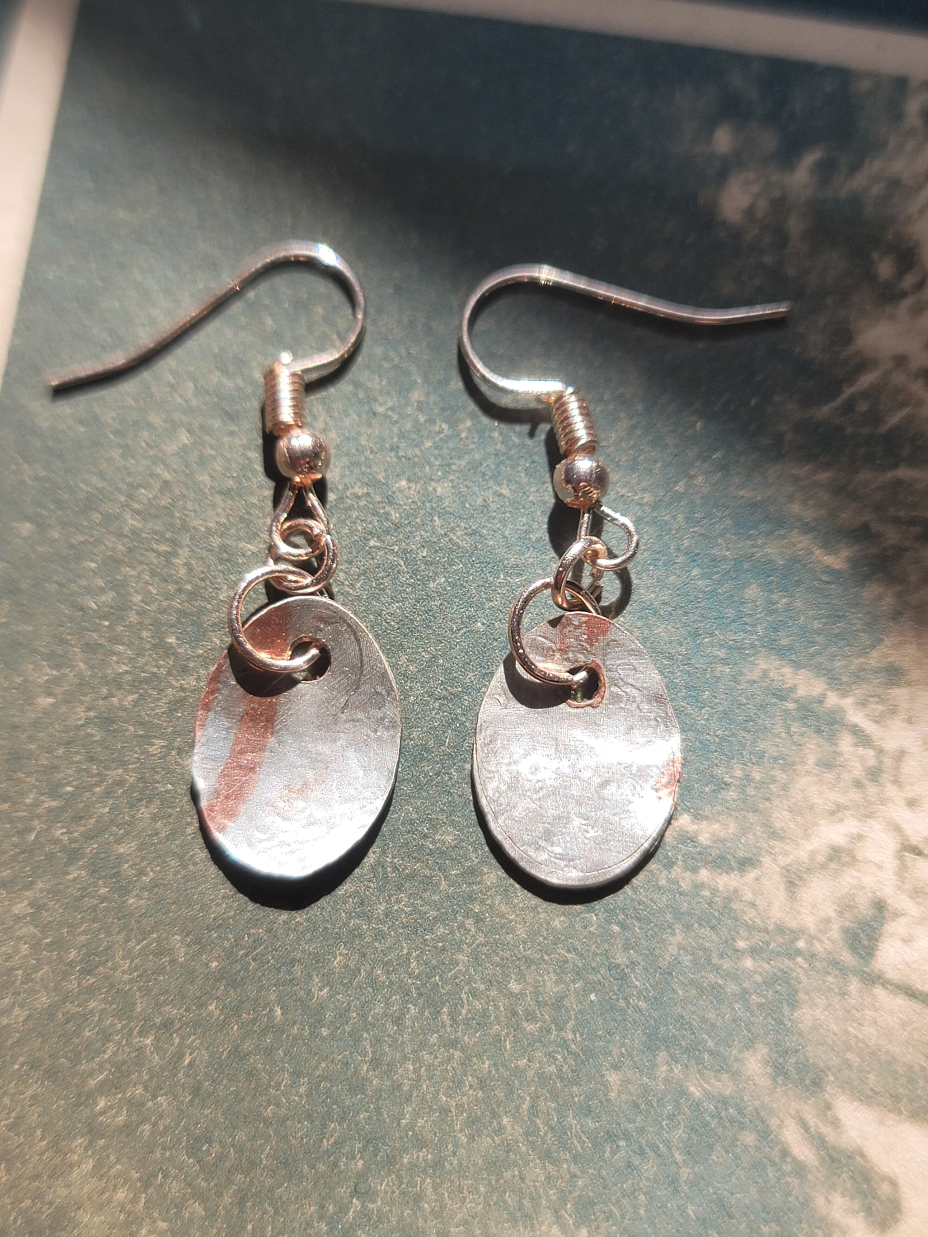 Pair of silver earrings on a textured green surface
